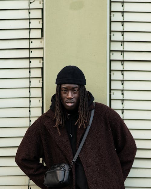 Man in a Brown Coat and a Beanie Standing against the Wall 