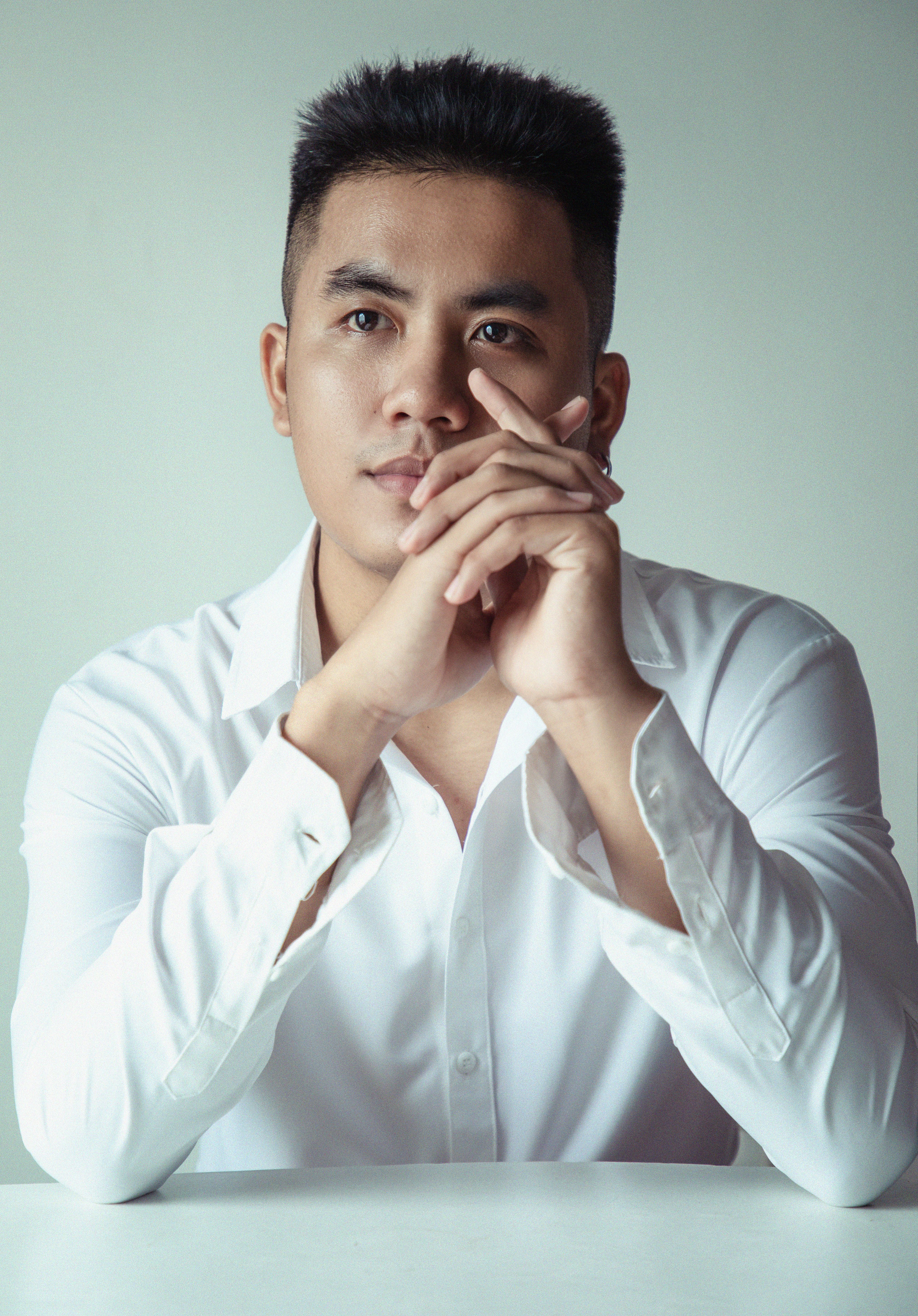 Expressive portrait of a man thoughtfully sitting at a table in a white shirt.