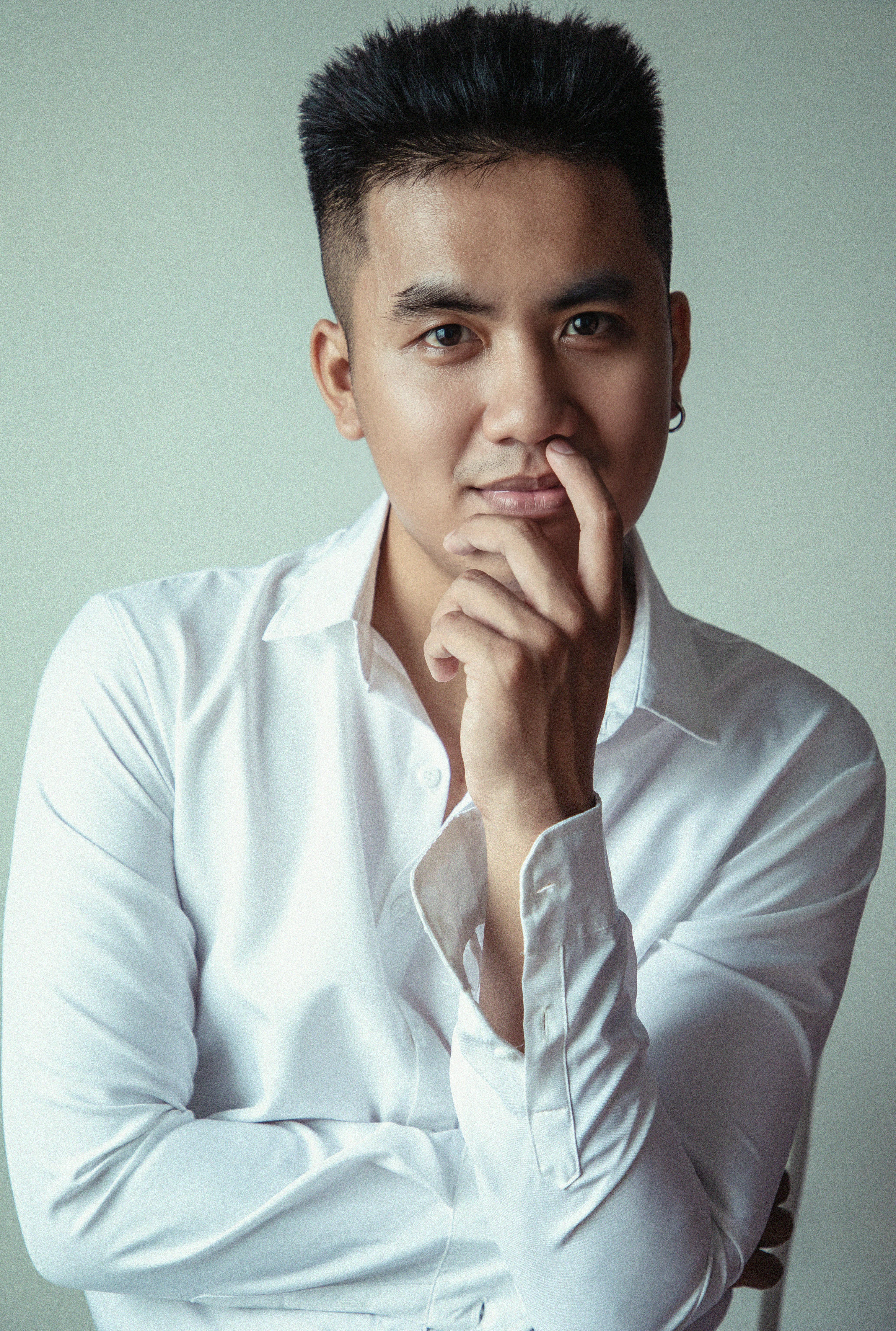 Portrait of a man wearing a white shirt, posing thoughtfully, in a studio setting.