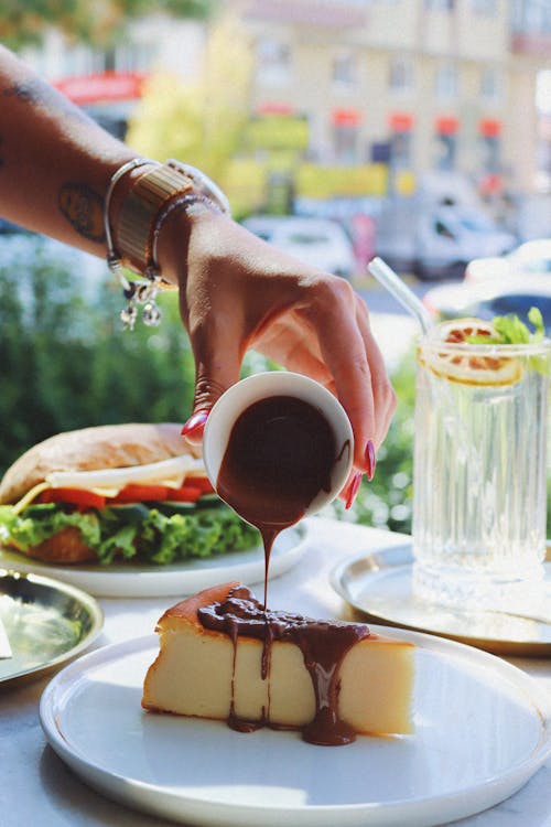 Woman Pouring Liquid Chocolate on Cheesecake