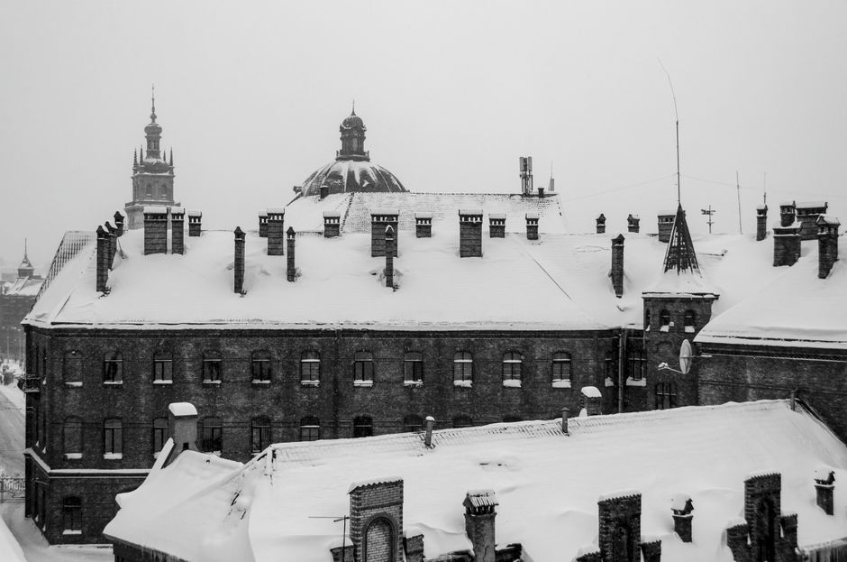 Black and white photo of snow-covered rooftops in wintery Lviv, Ukraine, capturing urban architecture.