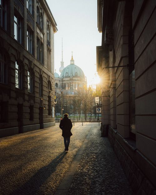 Free A lone figure walking towards the Berlin Cathedral during sunrise on a deserted street. Stock Photo