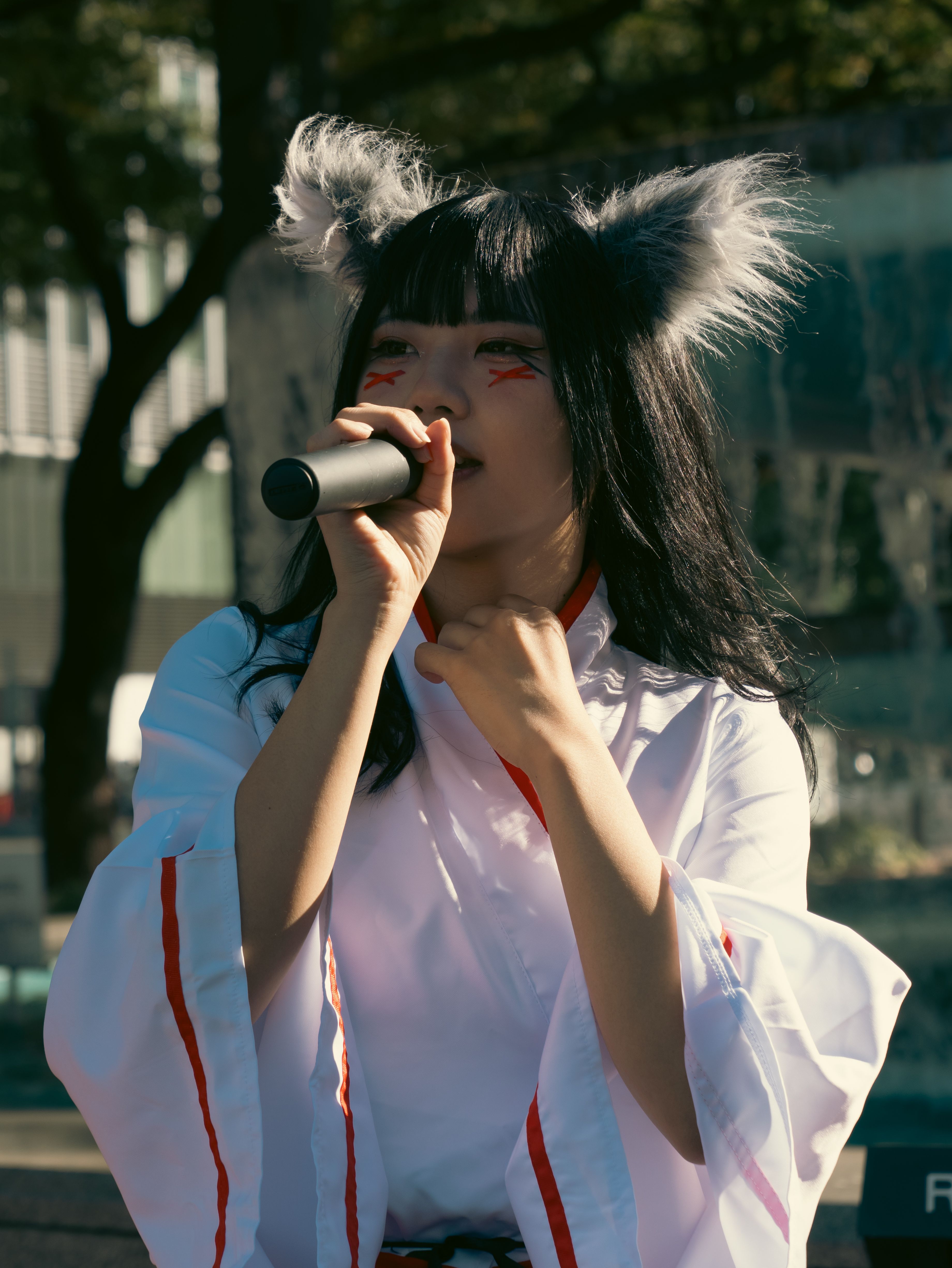 Cosplay performer singing outdoors in Nagoya with playful costume and microphone.