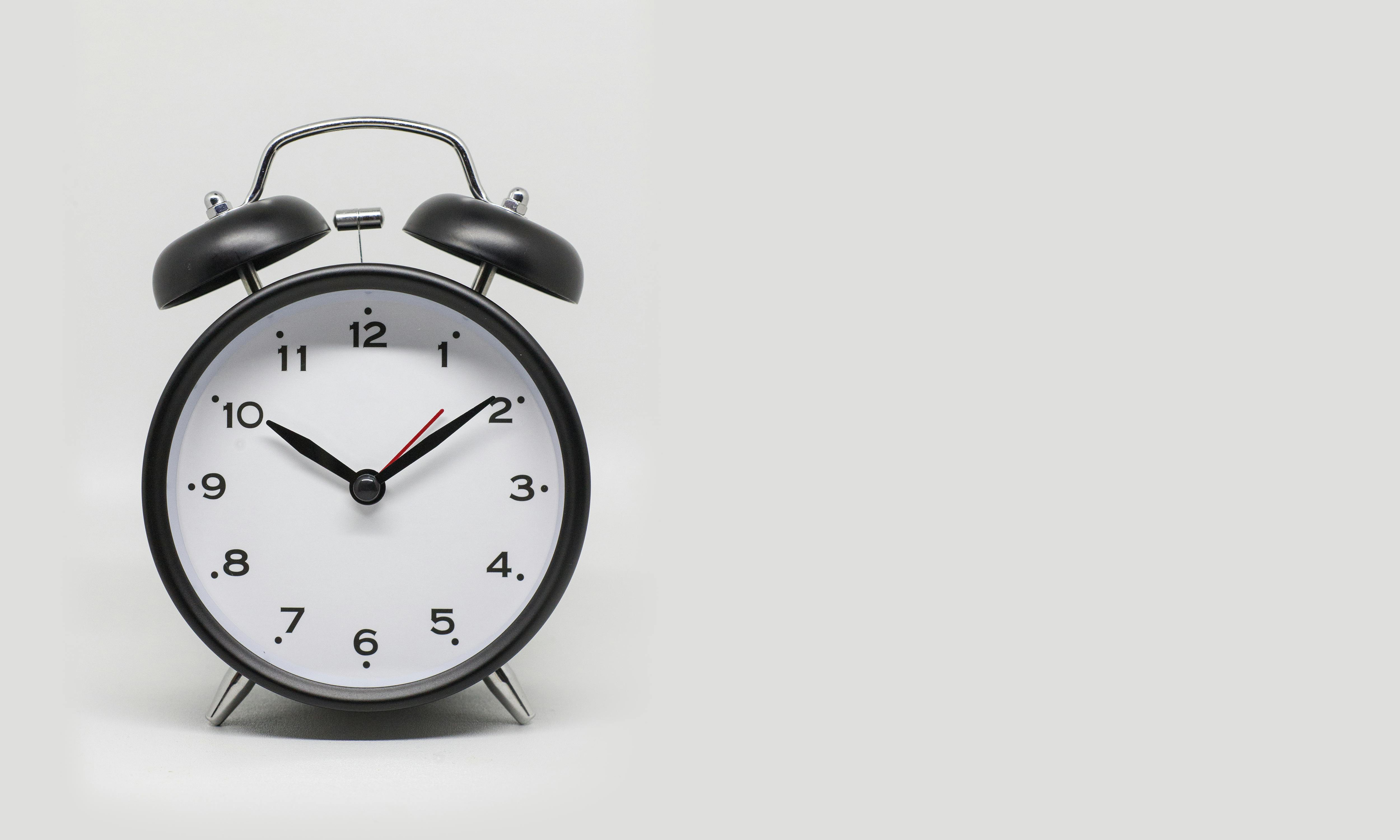 Close-up of a vintage black and white alarm clock on a white background.