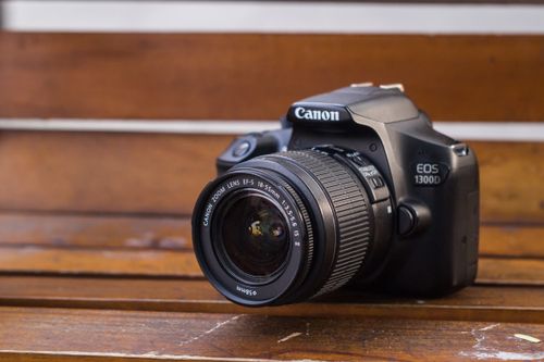 Free Close-up of a Canon DSLR camera resting on a rustic wooden bench. Stock Photo