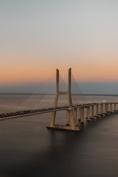 Breathtaking view of Vasco da Gama Bridge over calm waters at sunset, Lisbon, Portugal.