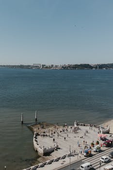 A beautiful aerial shot of Lisbon's waterfront with people enjoying a sunny day by the water.