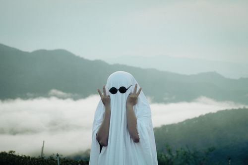 Free Person dressed in ghost costume poses playfully in mountainous fog, Da Lat. Stock Photo
