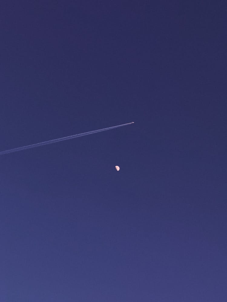 Plane Leaving Contrails Above The Moon