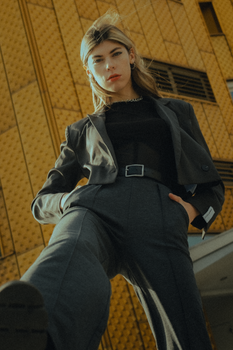 Stylish woman in a gray suit posing with a modern building in Berlin.