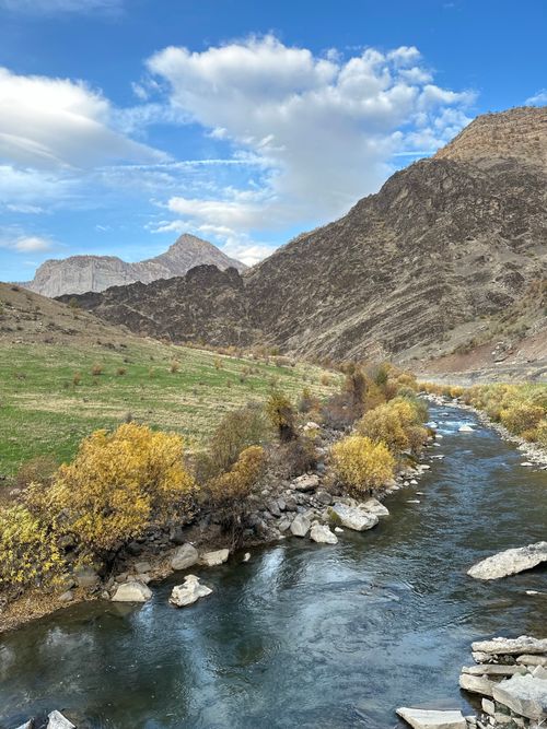 Free A beautiful autumn landscape featuring a flowing river through rugged mountains and colorful foliage. Stock Photo