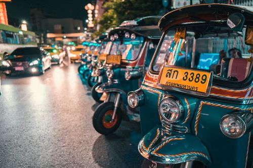 Free Vibrant row of tuk-tuks at night, illuminating the busy Thai city streets. Stock Photo