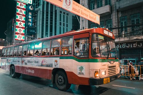 Free A vintage bus navigates the neon-lit streets of Bangkok at night, showcasing vibrant city life. Stock Photo