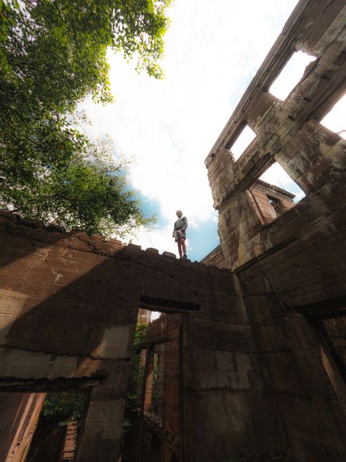 Free Person standing on the top of an abandoned ruin amidst nature, under a bright sky. Stock Photo
