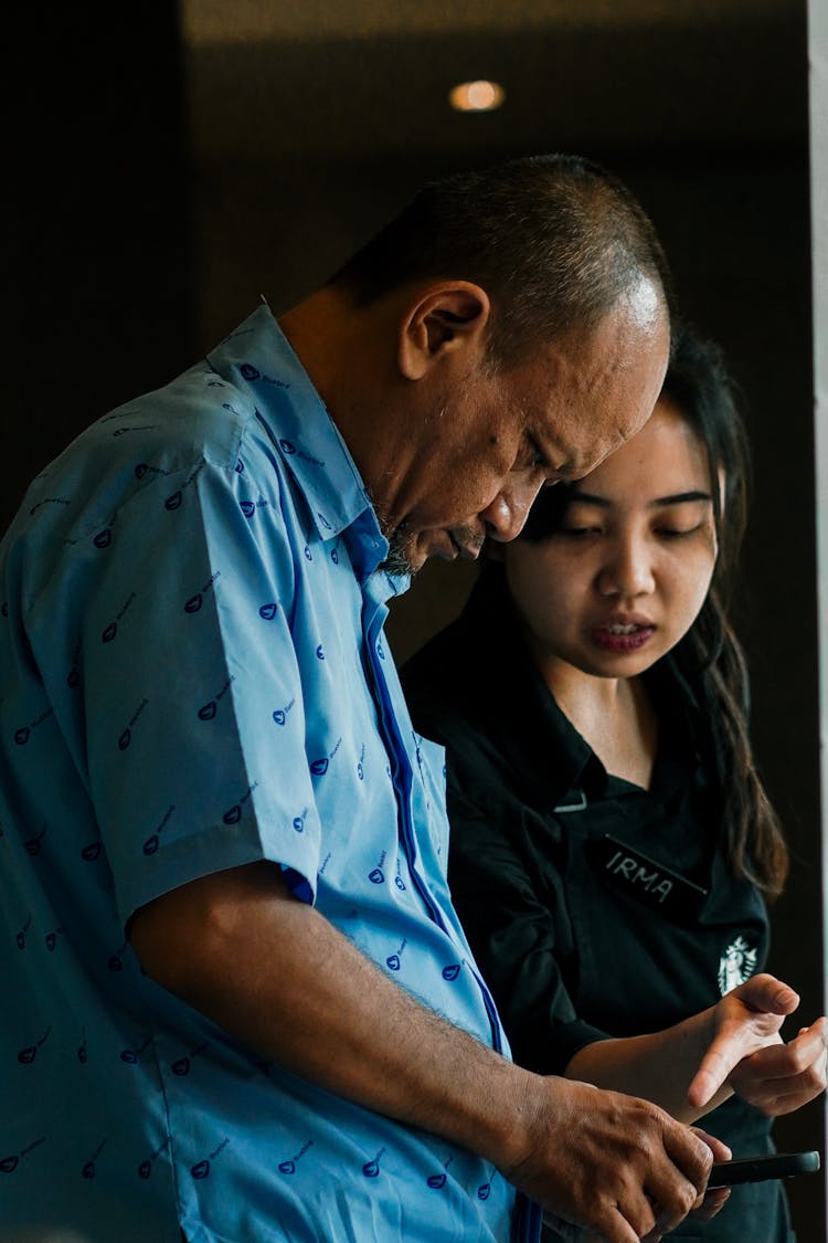 Asian Couple Looking At Cellphone Screen