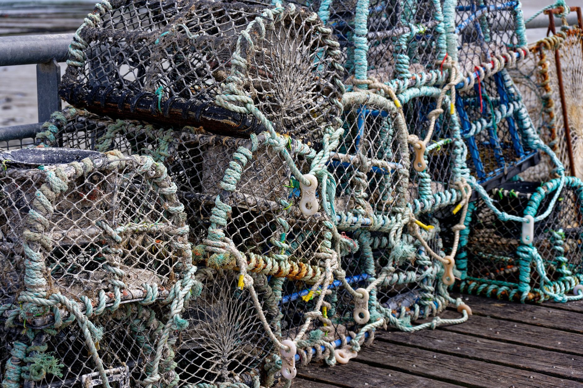 Close-up of stacked fishing traps on a wooden pier, showcasing marine industry tools.