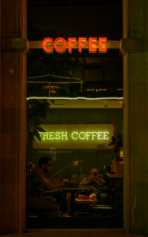 Free Relaxed evening in a Baku café with neon lights and patrons enjoying coffee. Stock Photo