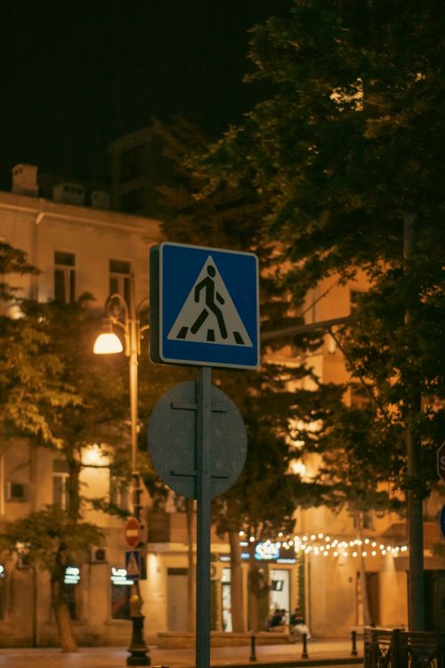 Free Illuminated urban crosswalk sign against a backdrop of city lights at night. Stock Photo