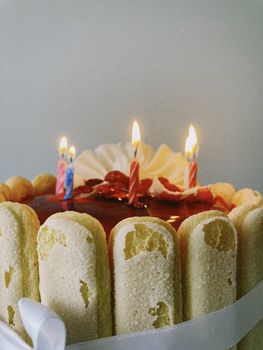 Close-up of a strawberry torte cake with lit candles, perfect for celebrations.