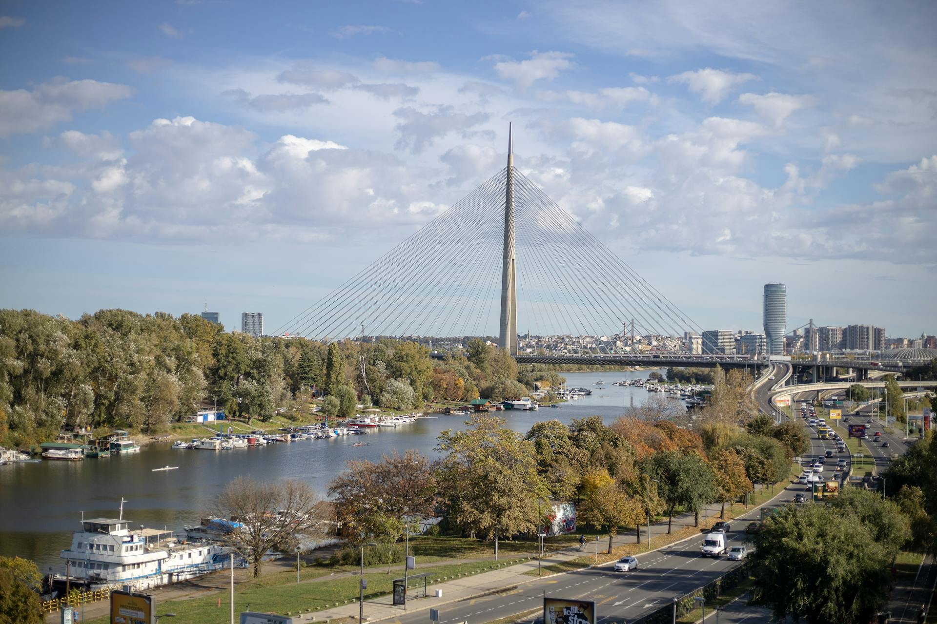 Aerial view of Ada Bridge and cityscape in Belgrade, Serbia with lush trees and river.