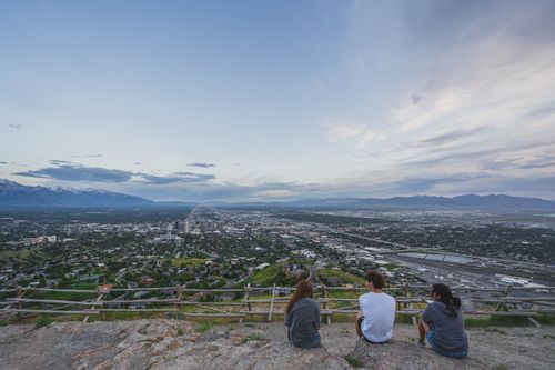 Free Group of friends sitting on a hill enjoying the panoramic cityscape view. Stock Photo