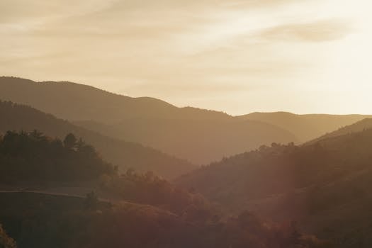 Serene sunrise view over foggy hills with warm tones capturing tranquility and beauty.