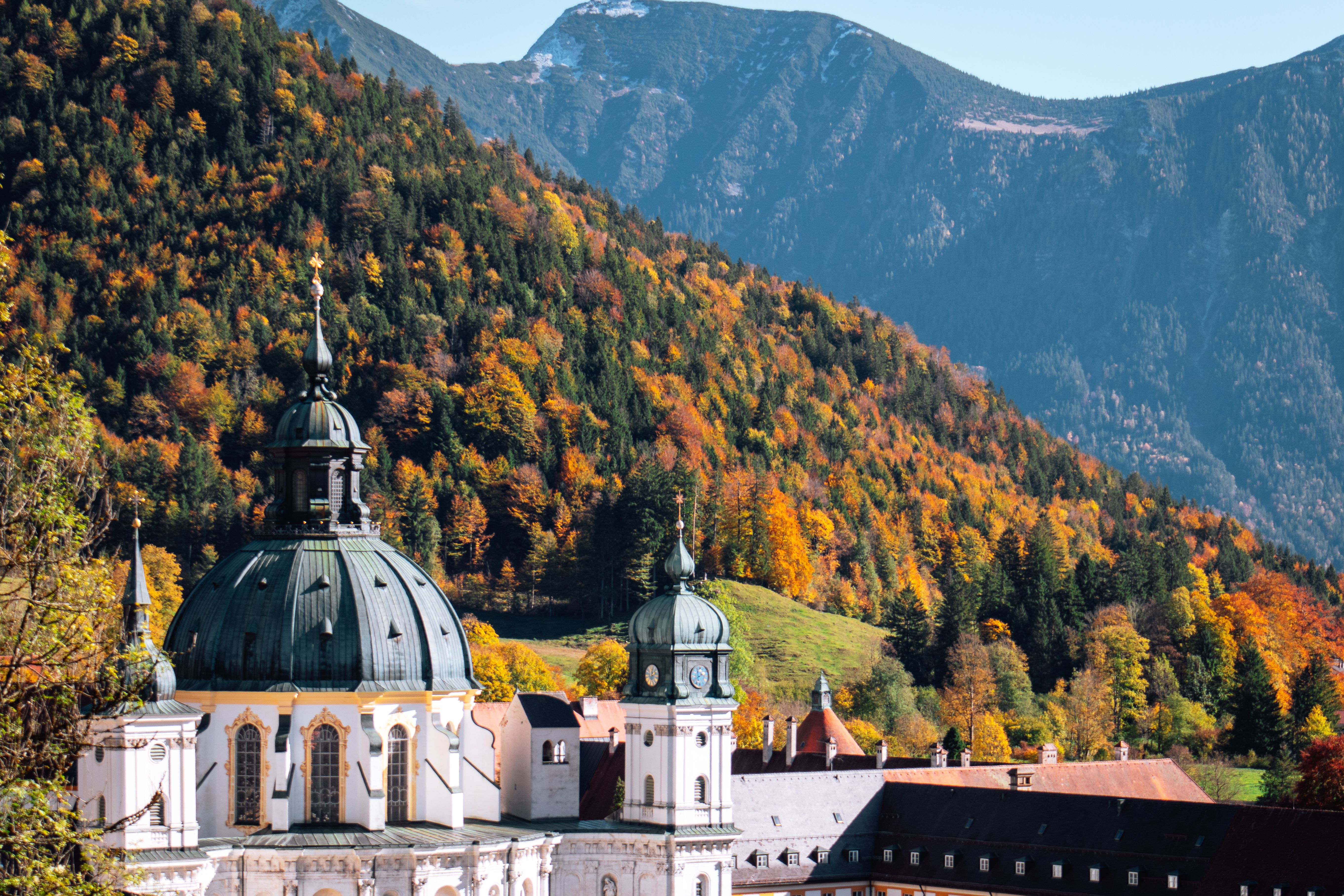 Ettal Abbey set against a vivid autumn forest in Germany's Bavarian Alps.
