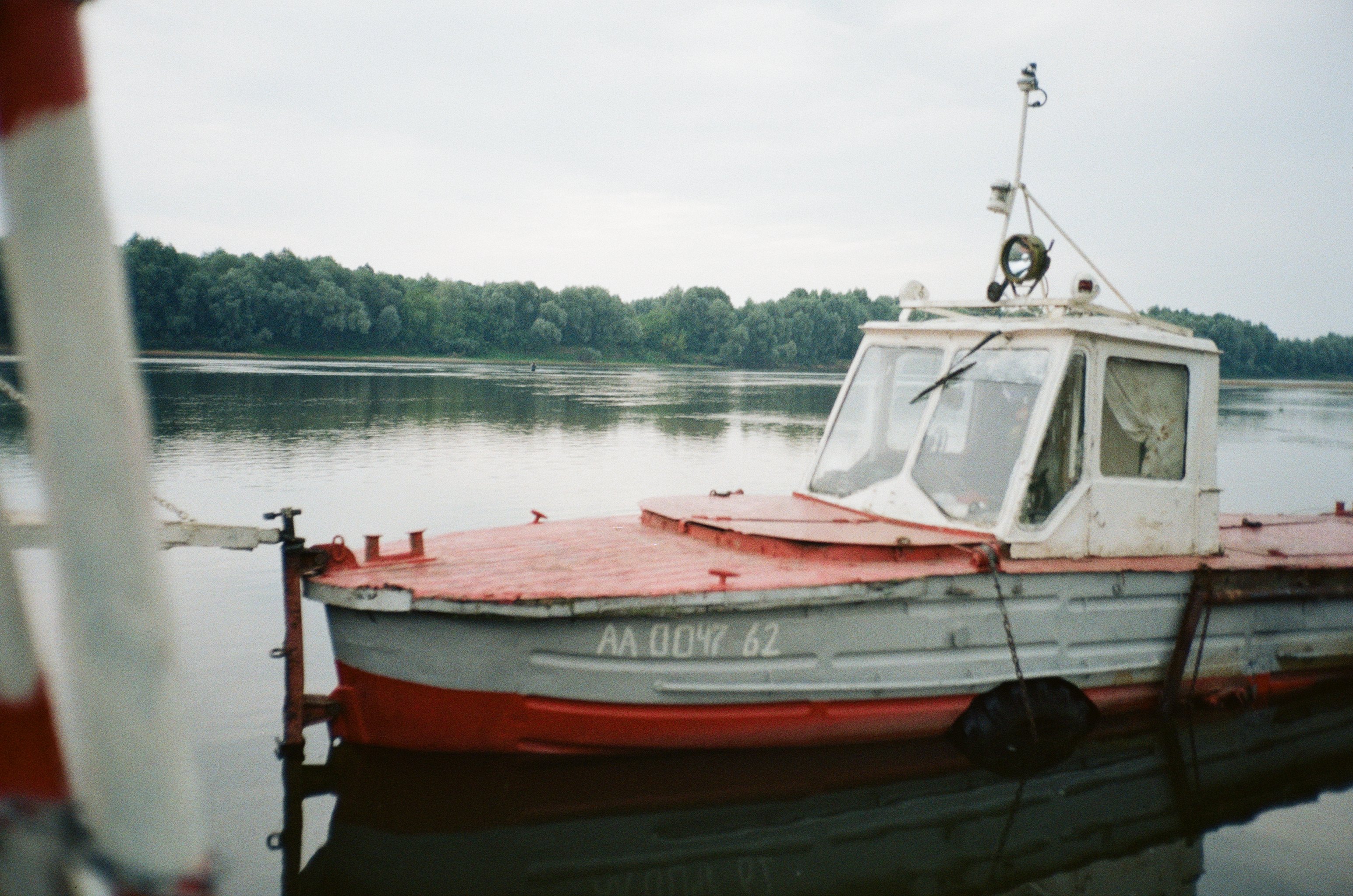 A vintage motorboat moored on a tranquil lake, surrounded by lush greenery and calm waters.