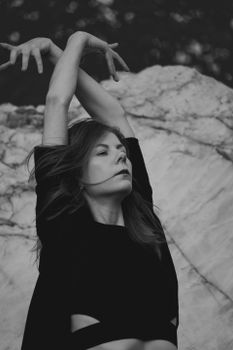 Expressive black and white portrait of a woman dancing gracefully with natural backdrop.