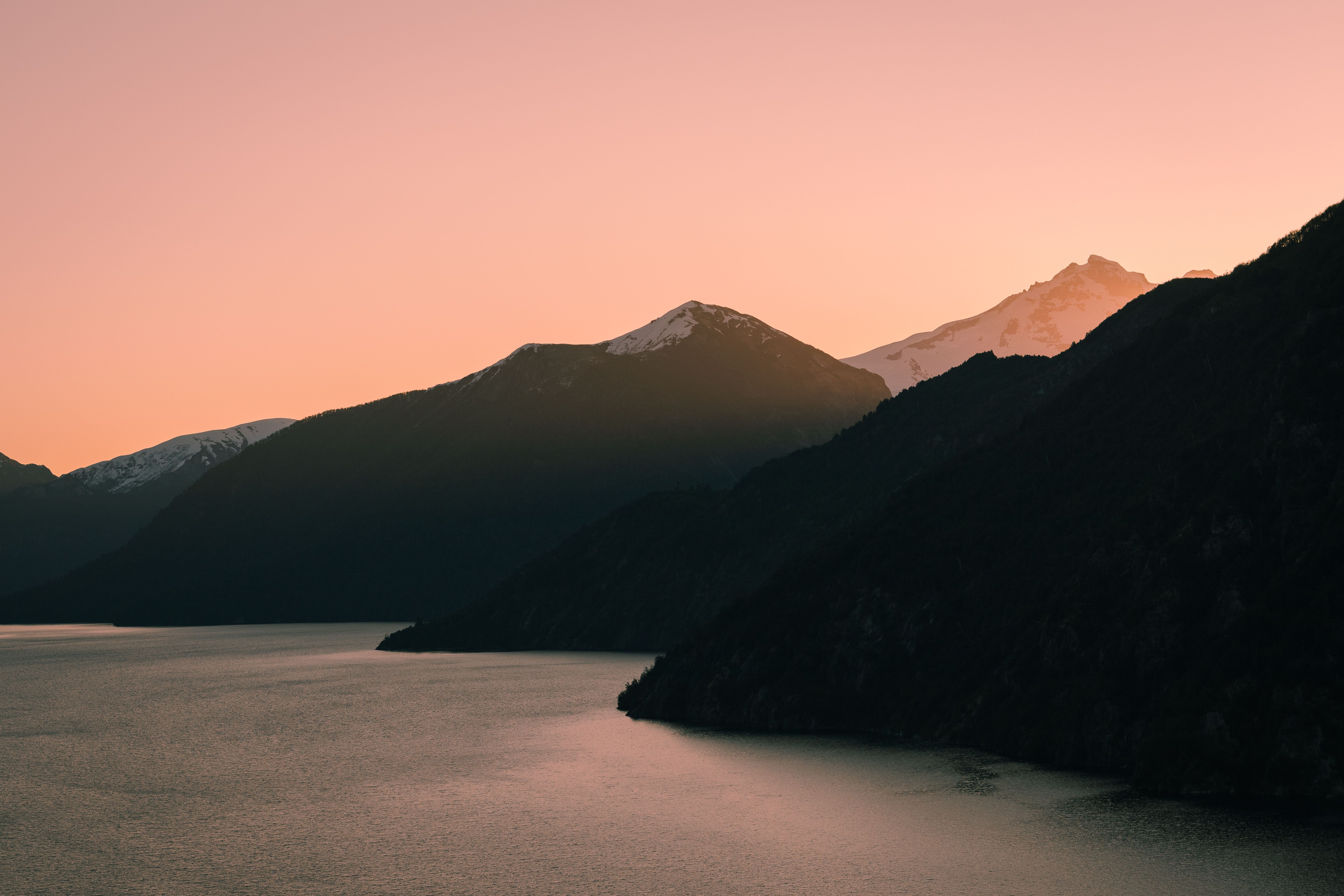 Breathtaking view of Bariloche mountains and lake under a pink sunset sky.