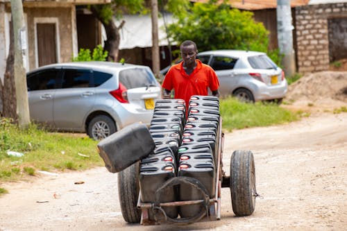 Man with pushing a cart with jerrycans of water