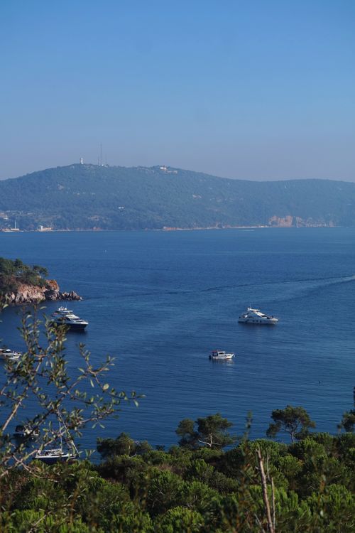 Free A serene bay with motorboats cruising along a beautiful coastline under a summer sky. Stock Photo