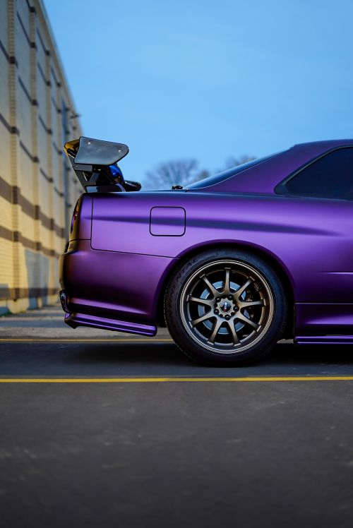 Free Stunning purple car with spoiler parked on city street at dusk. Stock Photo