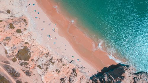 Free Stunning aerial shot of a beach with vibrant umbrellas and visitors enjoying the sun. Stock Photo