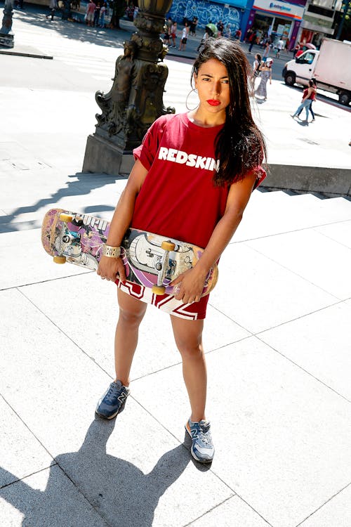 Woman Wearing Red Shirt Holding Skateboard
