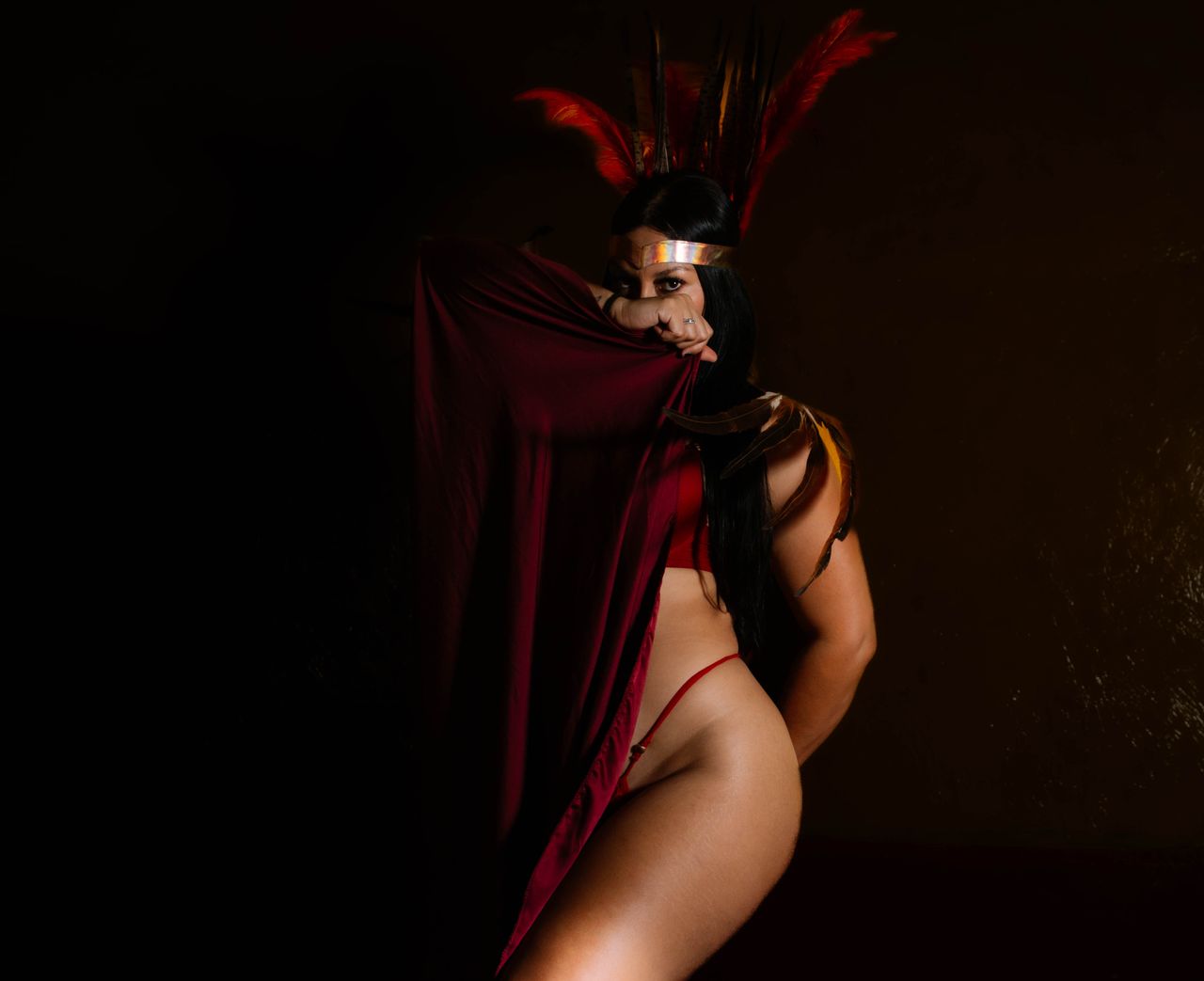 a captivating studio portrait of a woman in a feather headdress and re