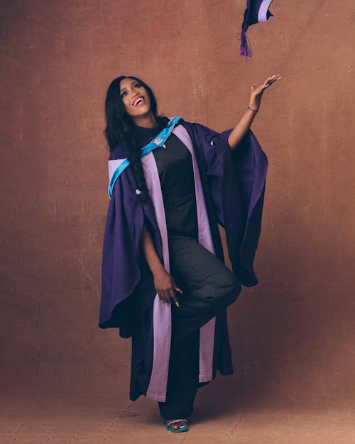 Smiling Woman in Graduation Gown Throwing Hat