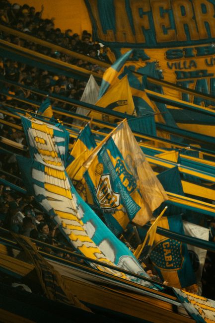 Fans displaying Boca Juniors flags in a stadium, showcasing vibrant team spirit and excitement.