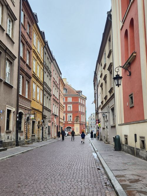 Free Cobblestone street in Warsaw's Old Town with colorful historic buildings and people walking. Stock Photo