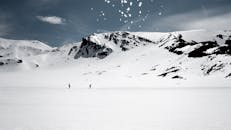 在多云的天空下，风景优美的雪山上有两名滑雪者