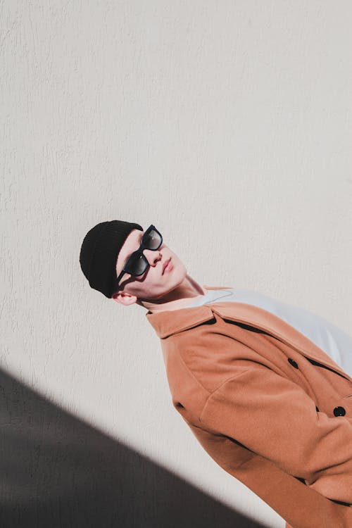 Young Stylish Man in Beanie and Sunglasses Posing near Wall