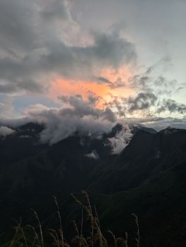 Serene view of Munnar mountains with dramatic clouds at twilight, capturing nature's tranquility.