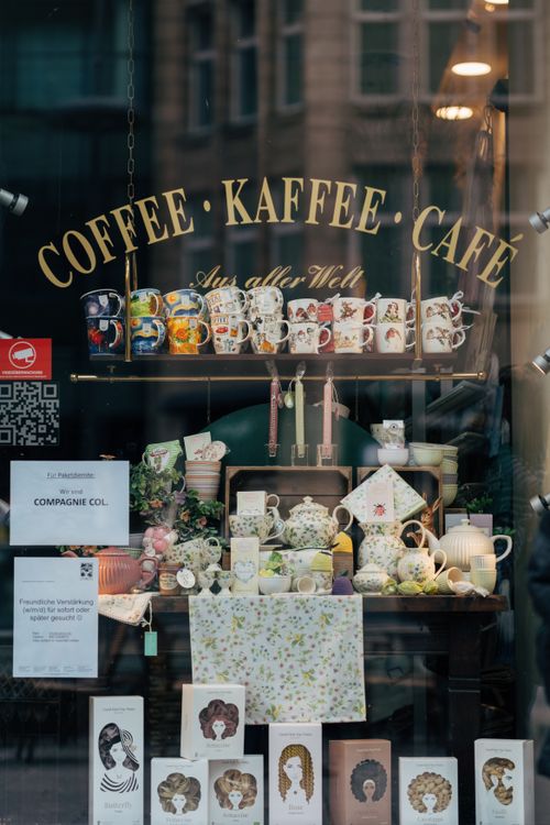 Free A delightful coffee shop window in Hamburg showcasing colorful mugs and decor. Stock Photo