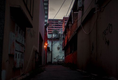 Free Dark urban alley at night with graffitied walls and distant city lights providing contrast. Stock Photo
