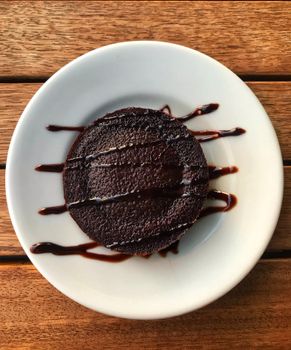 A top-down view of a moist chocolate cake with syrup drizzle on a white plate, perfect for dessert lovers.