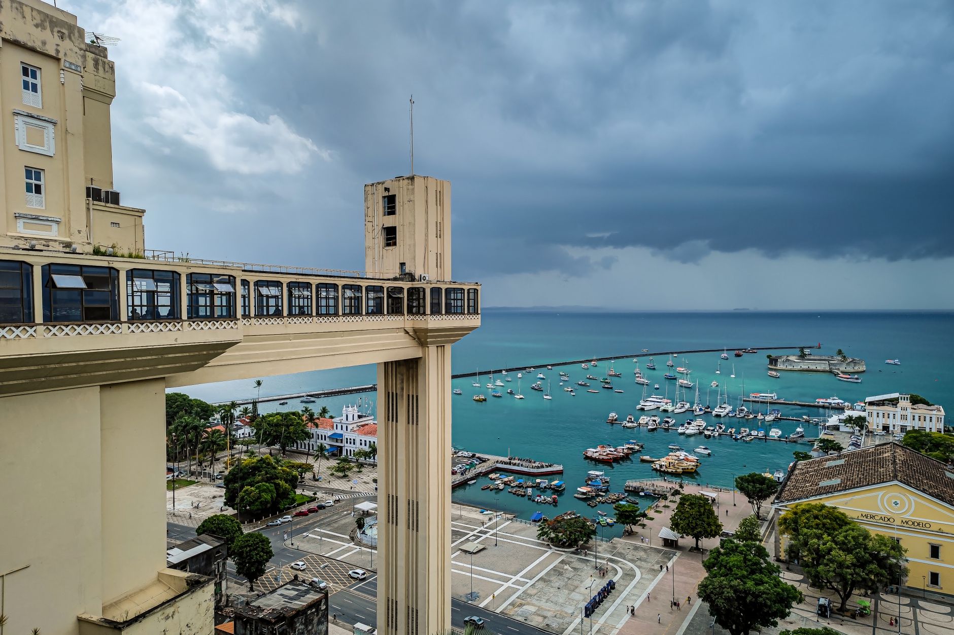 The art-deco tower and walkway of the Elevador Lacerda above Salvador's lower city, with boats and the Mercado Modelo on All Saints Bay below