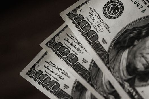 Detailed close-up image of US hundred dollar bills arranged in a fanned pattern.