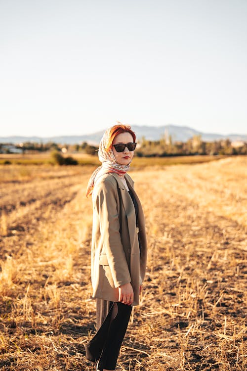 Woman in Sunglasses and a Headscarf Walking Through a Hayfield