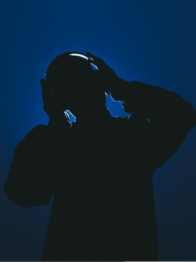 Silhouette Of A Man With Headphones Against Dark Blue Background