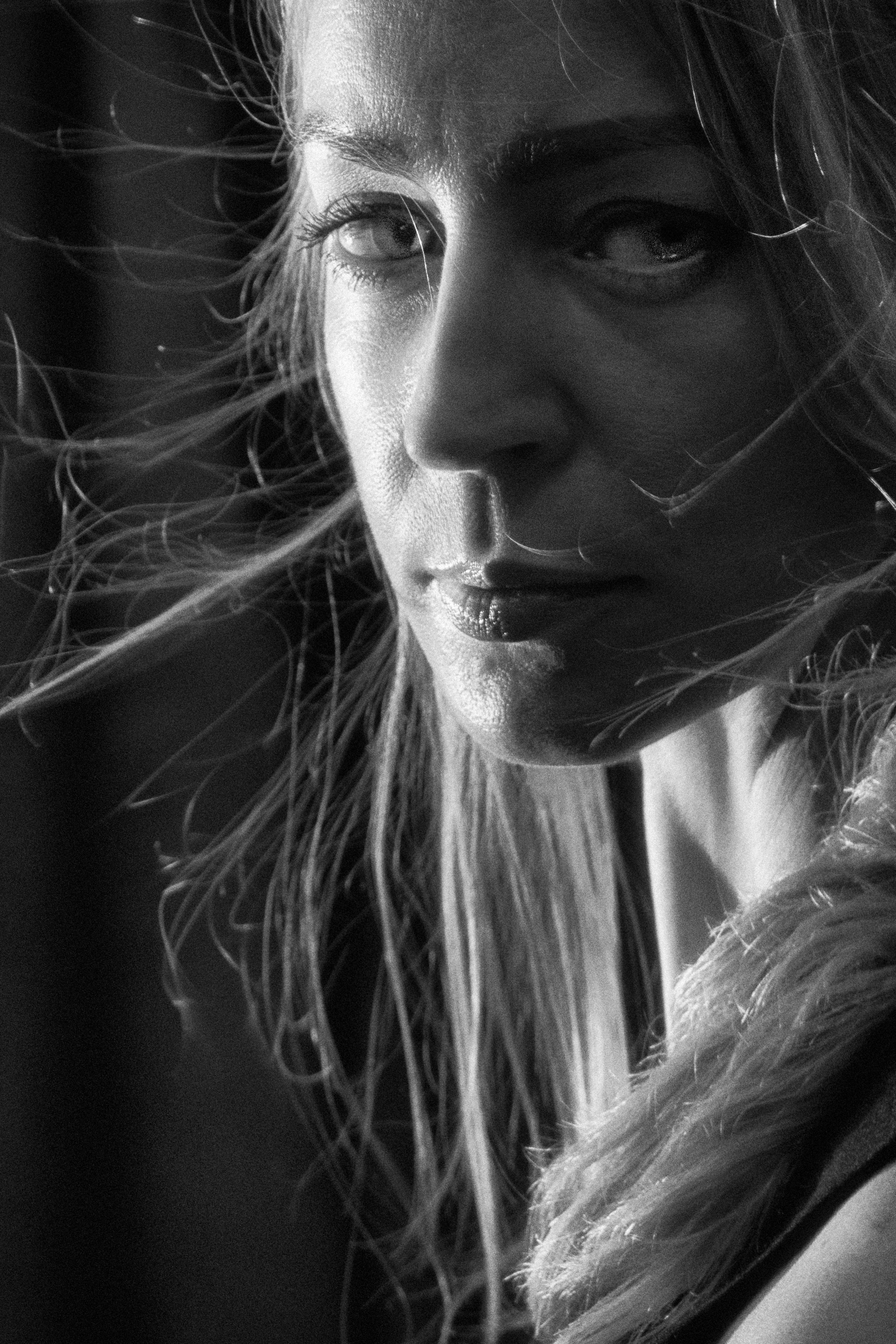 Close-up black and white photo of a pensive woman with wind-blown hair, expressing deep thoughts.